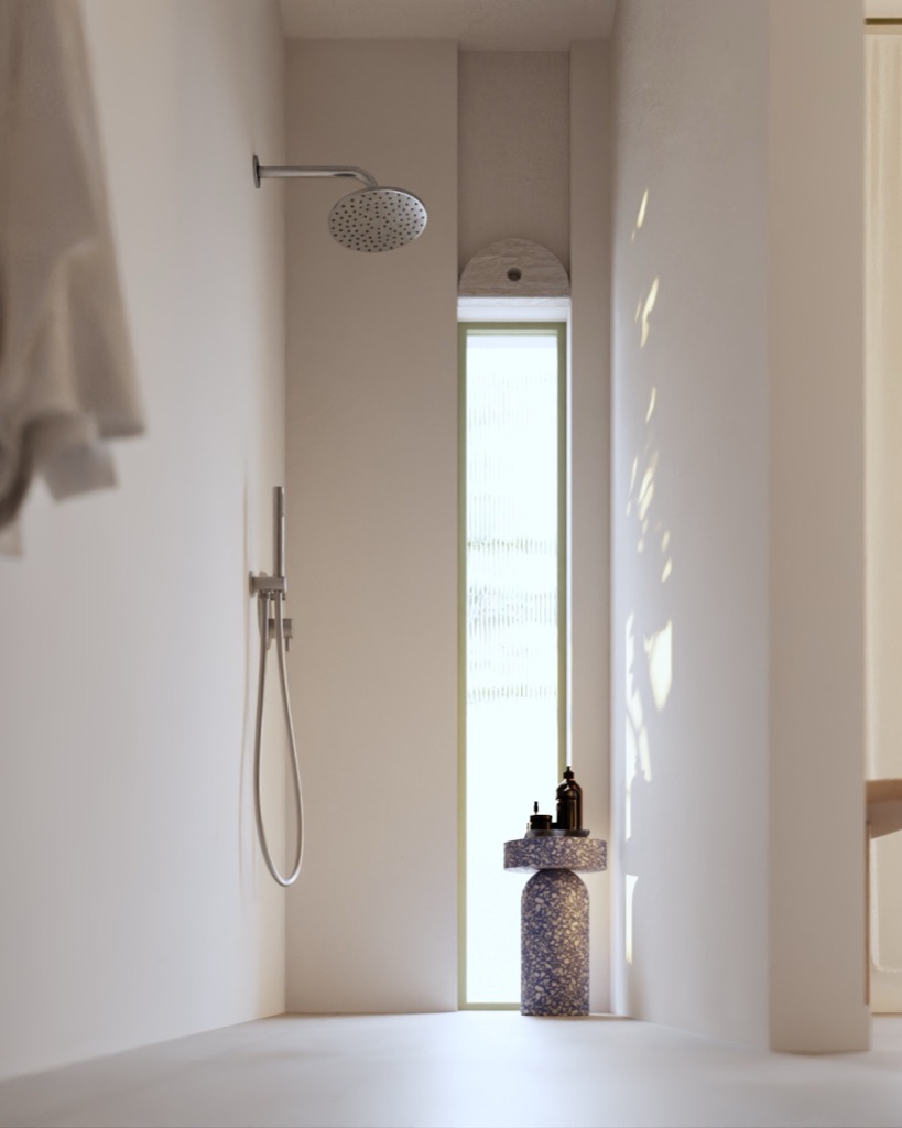A travertine bathroom with terrazzo stool and tall slot window.