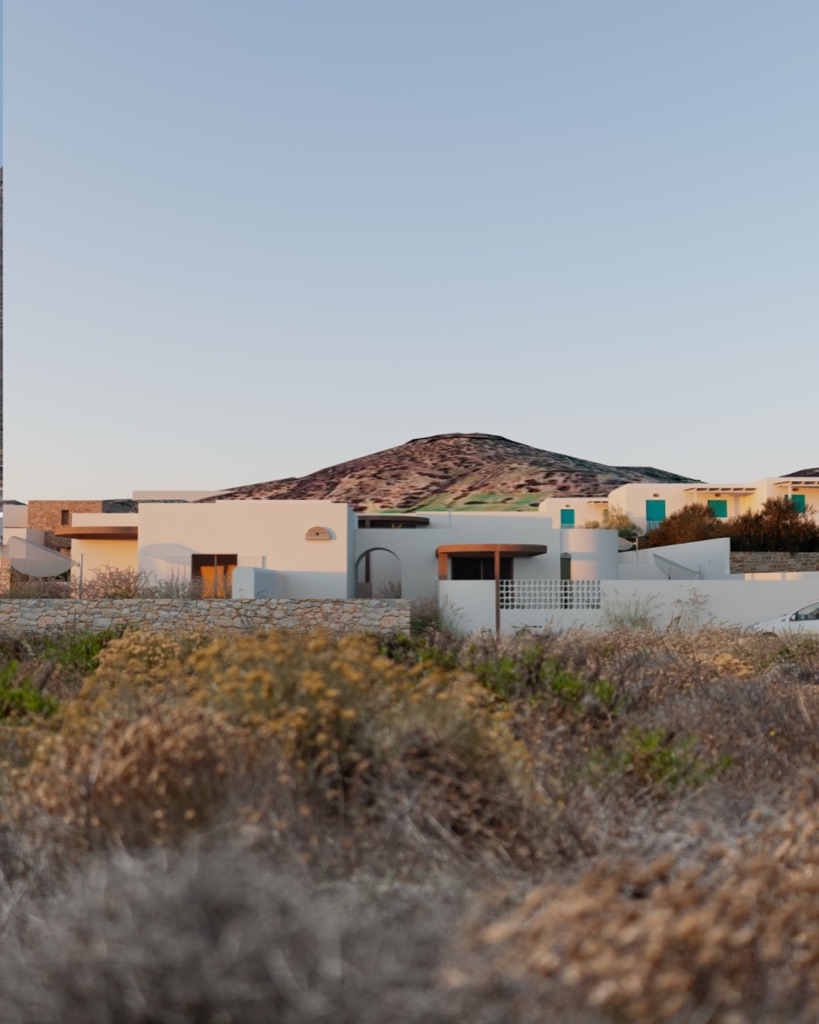 The Rastonee silhouette glimpsed through wild Cycladic grasses.