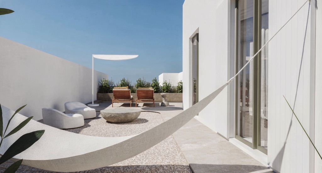 A white shade sail over loungers and a stone bowl on Nocturne's terrace.